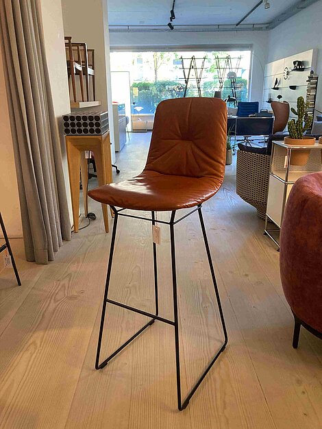 Moderner Barhocker mit braunem Lederbezug und schwarzem Metallgestell in einem Möbelgeschäft