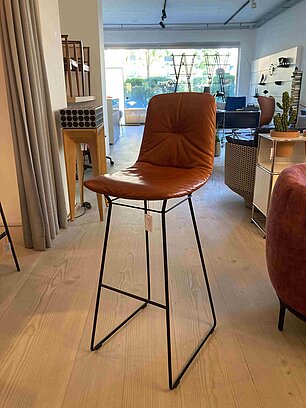 Moderner Barhocker mit braunem Lederbezug und schwarzem Metallgestell in einem Möbelgeschäft