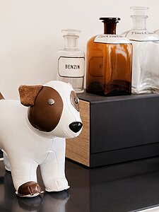 Dekorativer Hund aus Leder vor Retro-Flaschen auf Regal