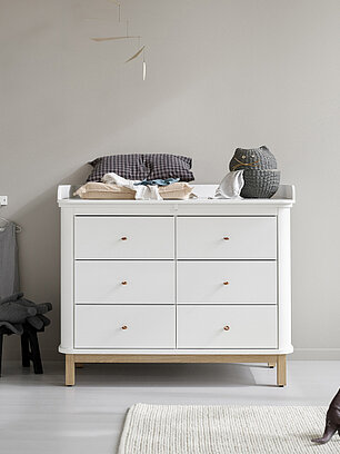 Weiße Kommode mit Wickelauflage im modernen Babyzimmer mit Spielzeug und Kinderkleidung