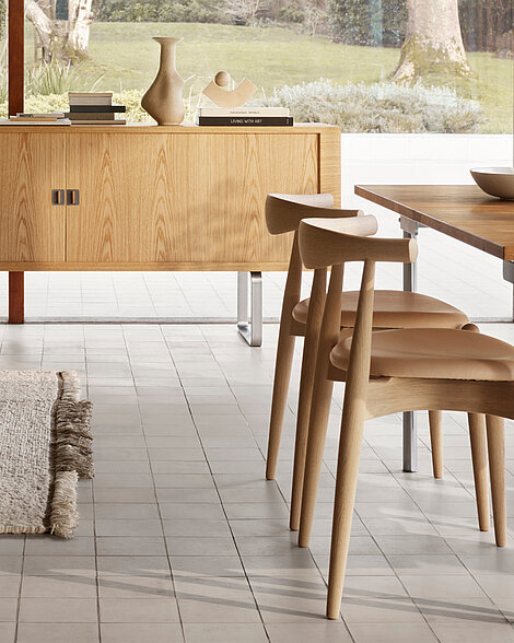 Modernes Esszimmer mit hellen Holzmöbeln, Keramikdeko und Blick in den Garten