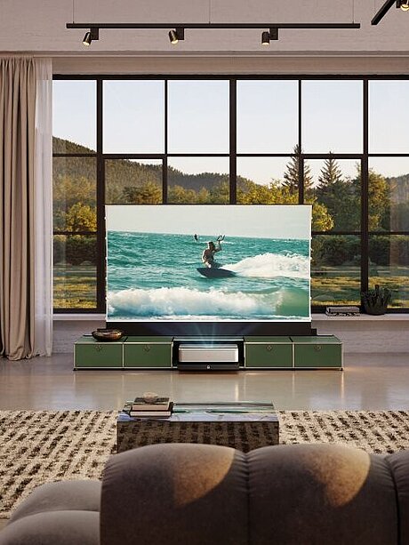Modern living room with large TV displaying a surfer and scenic window view