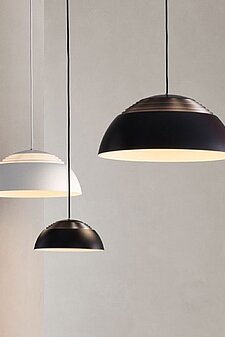 Drei moderne Pendelleuchten in Schwarz und Weiß vor einer neutralen Wand