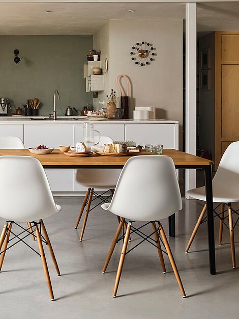 Moderne Küche mit Holz-Esstisch, weißen Stühlen und gedeckter Käseplatte