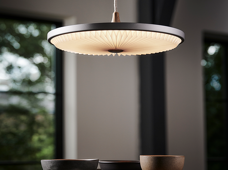 Moderne Pendelleuchte über gedecktem Tisch mit Keramikschalen bei natürlichem Licht
