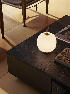 Modern table lamp with frosted glass shade on dark wooden coffee table in warm interior