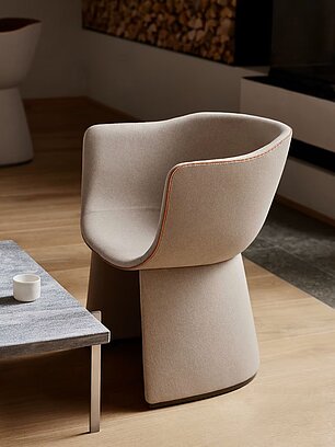 Modern beige armchair beside a sleek coffee table in a minimalist living room