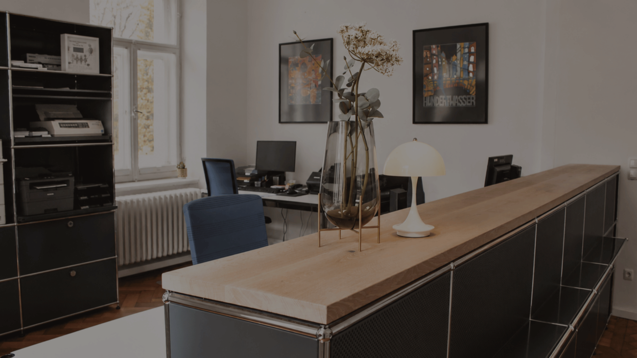 Modern office with wooden counter, vase, lamp, and framed art on walls