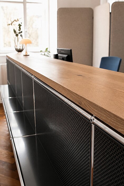 Modern reception desk with wooden counter and black metal paneling