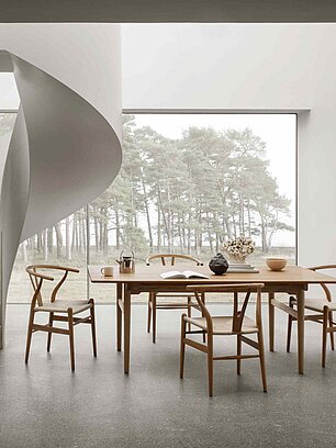 Modernes Esszimmer mit Holzstühlen, Holztisch und skulpturaler Wendeltreppe vor Panoramafenster