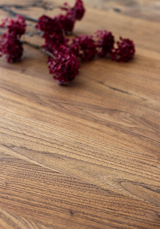 Verwischte rote Trockenblumen auf glatter Holzoberfläche aus Eichenholz