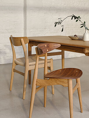 Zwei skandinavische Esszimmerstühle aus Holz an einem Holztisch mit minimalistischer Dekoration