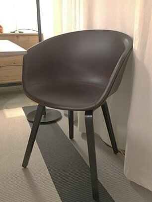 Moderner brauner Kunststoffstuhl mit schwarzen Beinen in einem Schlafzimmer mit Teppichboden