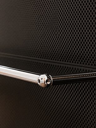 Metal rod with rounded end against perforated metal background