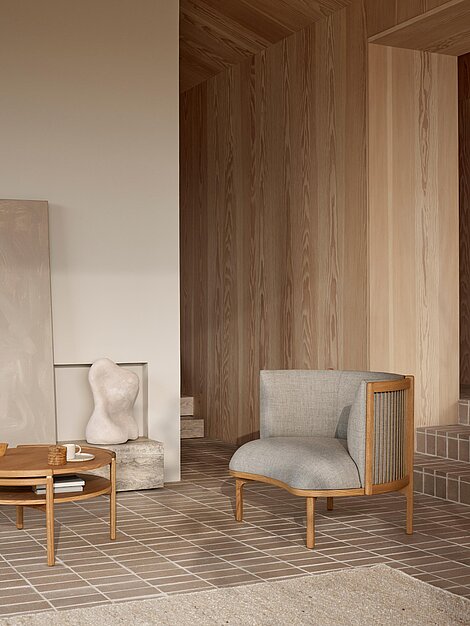 Modernes Wohnzimmer mit grauem Designerstuhl, Holztisch und Skulptur auf Fliesenboden