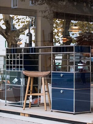USM Haller Barregal mit blauen Modulen, Barhocker und Weinflasche im Schaufenster