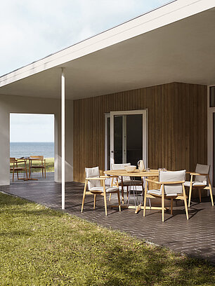 Moderne Terrasse mit Holzmöbeln und Meerblick neben einem Haus mit Holzfassade