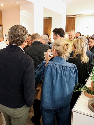 Group of people socializing in a bright, modern space with plants