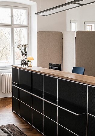 Modern office reception desk with beige partitions and decorative lamp