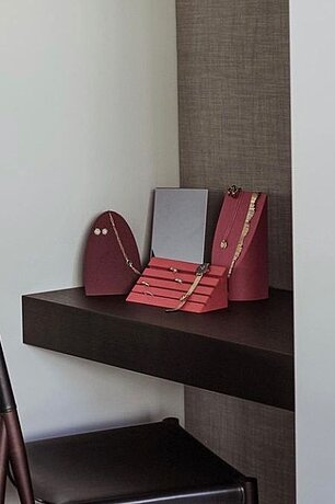 Schmuckständer mit Goldketten und Ohrringen auf dunklem Regal in einer modernen Nische