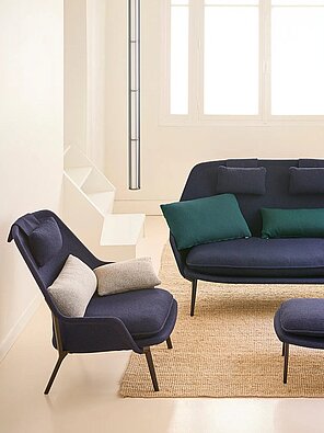 Modernes Wohnzimmer mit dunkelblauen Polstermöbeln und farbigen Kissen auf einem Juteteppich