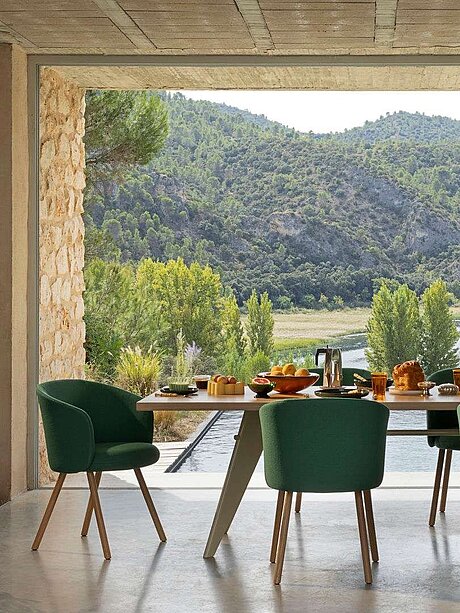 Esstisch mit grünen Stühlen und Frühstück, Blick auf bewaldete Landschaft