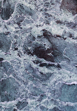 Tosende Meereswellen treffen auf dunkle Felsen in dramatischer Bewegung