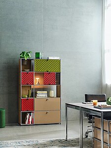 Modernes Büro mit Regal aus bunten Modulen und Schreibtisch mit schwarzen Stühlen