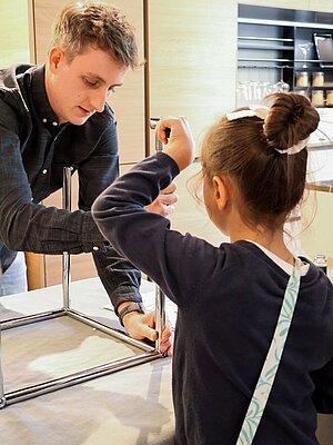 Adult and child assembling a metal chair frame in kitchen setting
