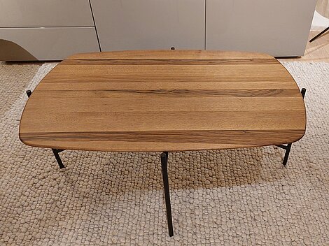 Rechteckiger Couchtisch aus Holz mit schwarzen Metallbeinen auf einem beigen Teppich