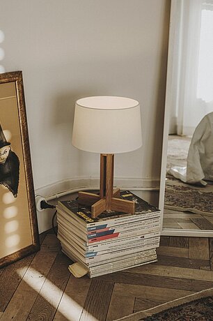 Table lamp with wooden base on stacked magazines in a cozy room