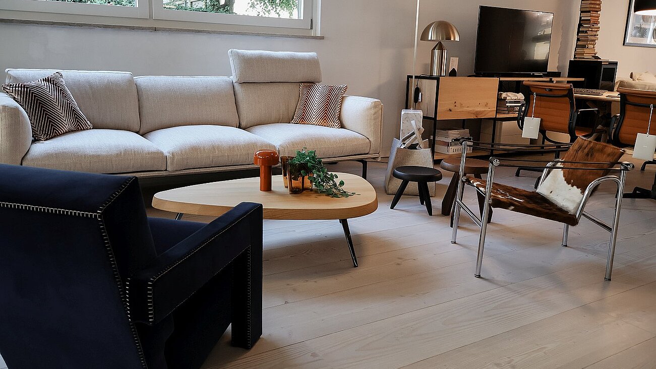 Modern living room with beige sofa, black armchair, cowhide chair, and wooden coffee table