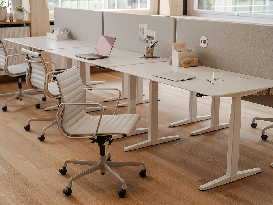 Modernes Großraumbüro mit weißen Schreibtischen, ergonomischen Stühlen und Laptops auf Holzfußboden