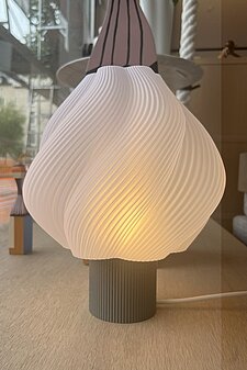 Moderne Tischlampe mit gedrehtem weißen Lampenschirm auf geriffeltem Sockel im skandinavischen Stil