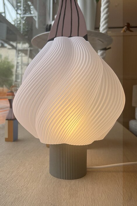Moderne Tischlampe mit gedrehtem weißen Lampenschirm auf geriffeltem Sockel im skandinavischen Stil