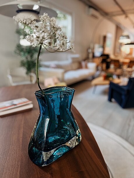 Blaue Glasvase mit weißer Blume in modernem Wohnzimmer