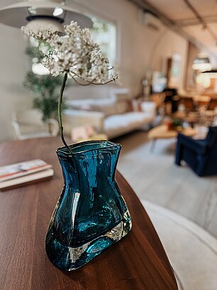 Blaue Glasvase mit weißer Blume in modernem Wohnzimmer