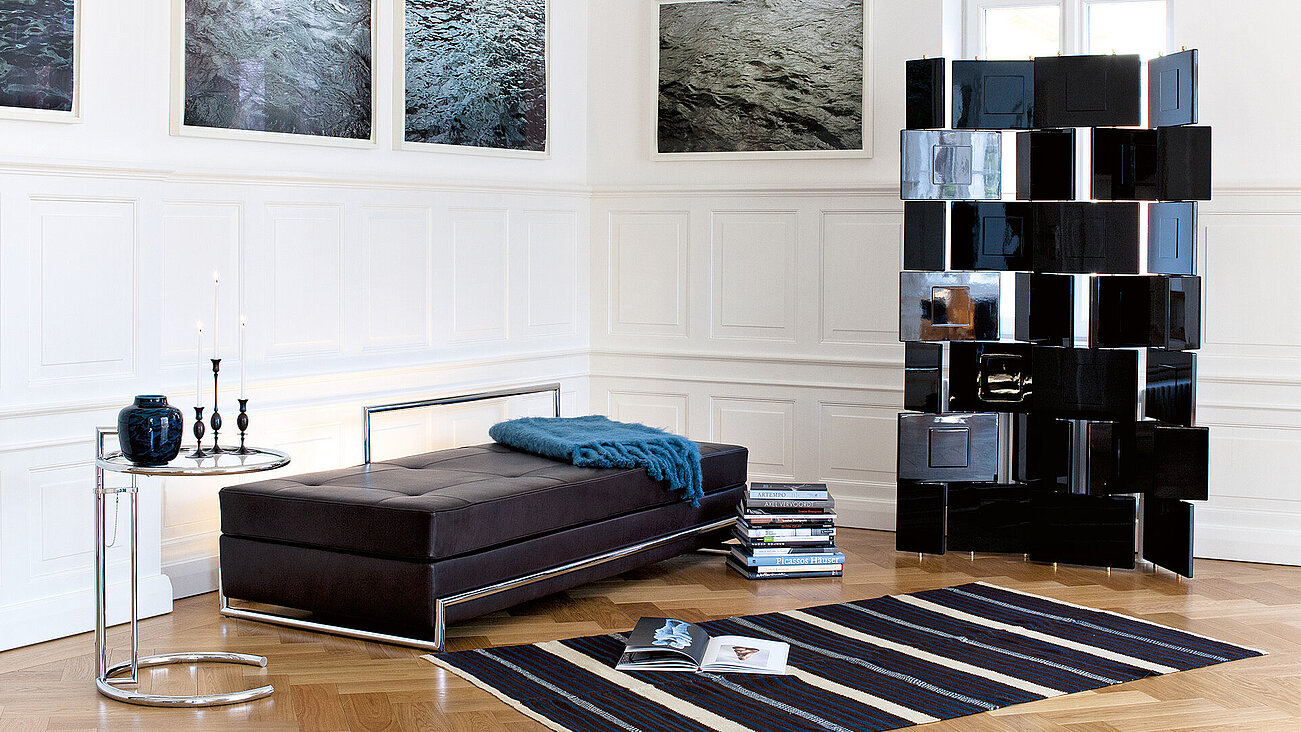 Modernes Wohnzimmer mit Ledersofa, schwarzem Paravent, Kunst an den Wänden und gestreiftem Teppich