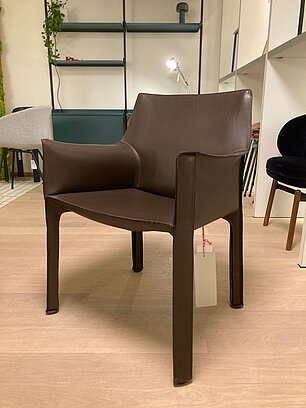 Moderner brauner Lederstuhl mit Armlehnen auf hellem Holzboden in einem Designmöbelgeschäft