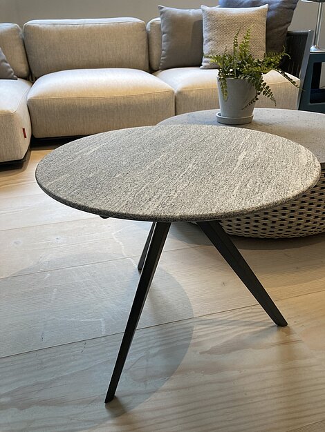 Runder Beistelltisch mit grauer Steinplatte vor einem beigen Sofa in modernem Wohnzimmer