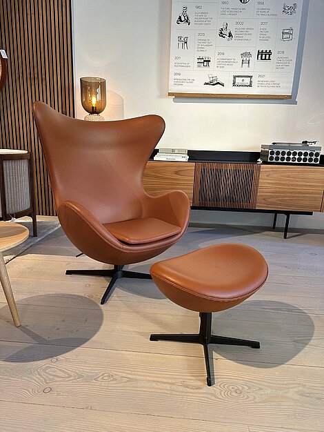 Modern brown leather armchair with matching ottoman in stylish room