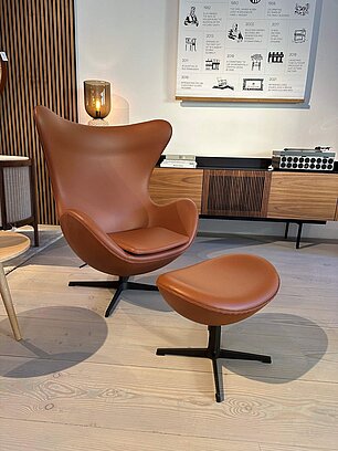 Modern brown leather armchair with matching ottoman in stylish room
