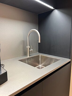 Moderne Edelstahlspüle mit Wasserhahn in minimalistischem schwarzem Küchenbereich