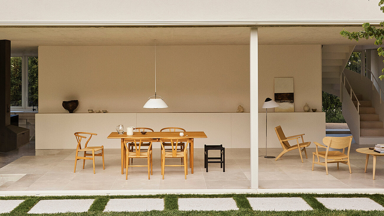 Modern white villa with outdoor seating, glass walls, and lush garden