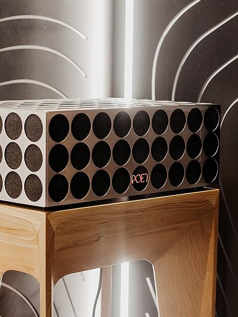 Designlautsprecher mit runden Gittern auf Holzständer vor modernem Hintergrund