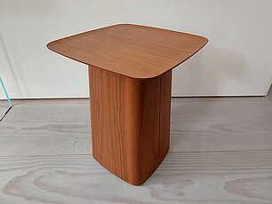 Moderner Beistelltisch aus Holz mit abgerundeter quadratischer Tischplatte auf hellem Holzboden