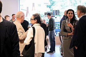 People socializing at business event, holding drinks in a modern setting