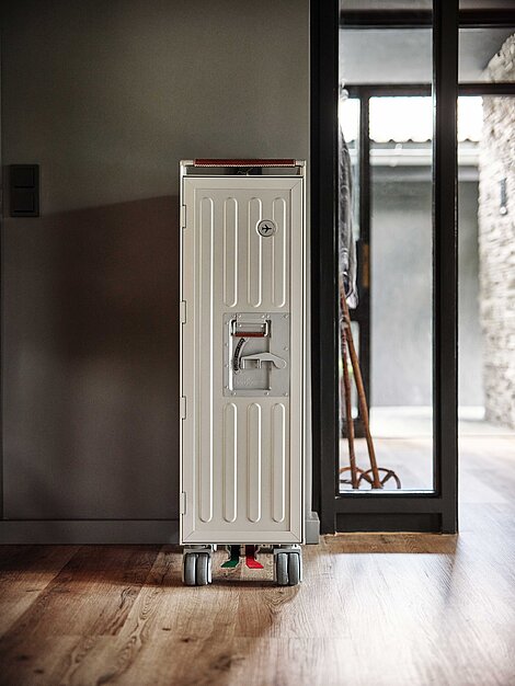 Weißer Flugzeugtrolley auf Rollen in modernem Innenraum mit Holzboden