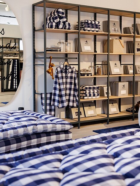 Bettenschauraum mit karierten Schlafanzügen, Kissen und Matratzen in Blau-Weiß