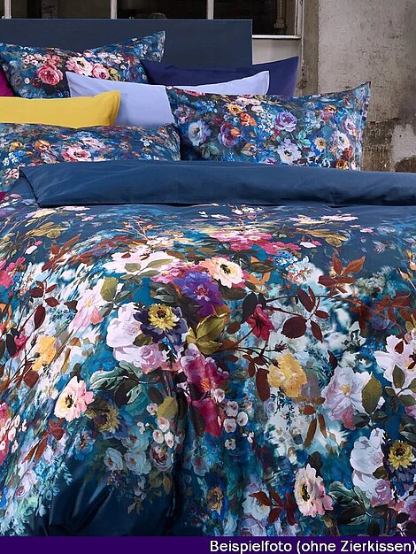 Bettwäsche mit buntem Blumenmuster auf blauem Hintergrund vor industrieller Wand